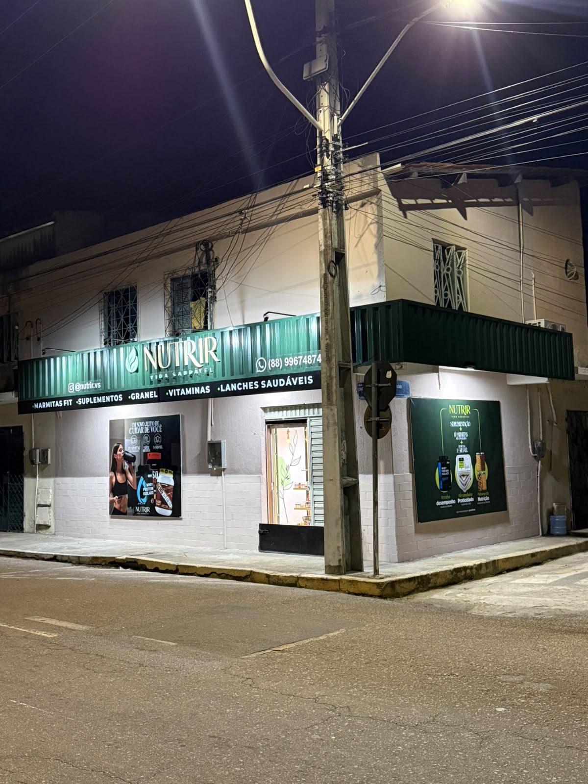 Fachada da Nutrir Vida Saudável durante o dia, com a lista de categorias no toldo verde